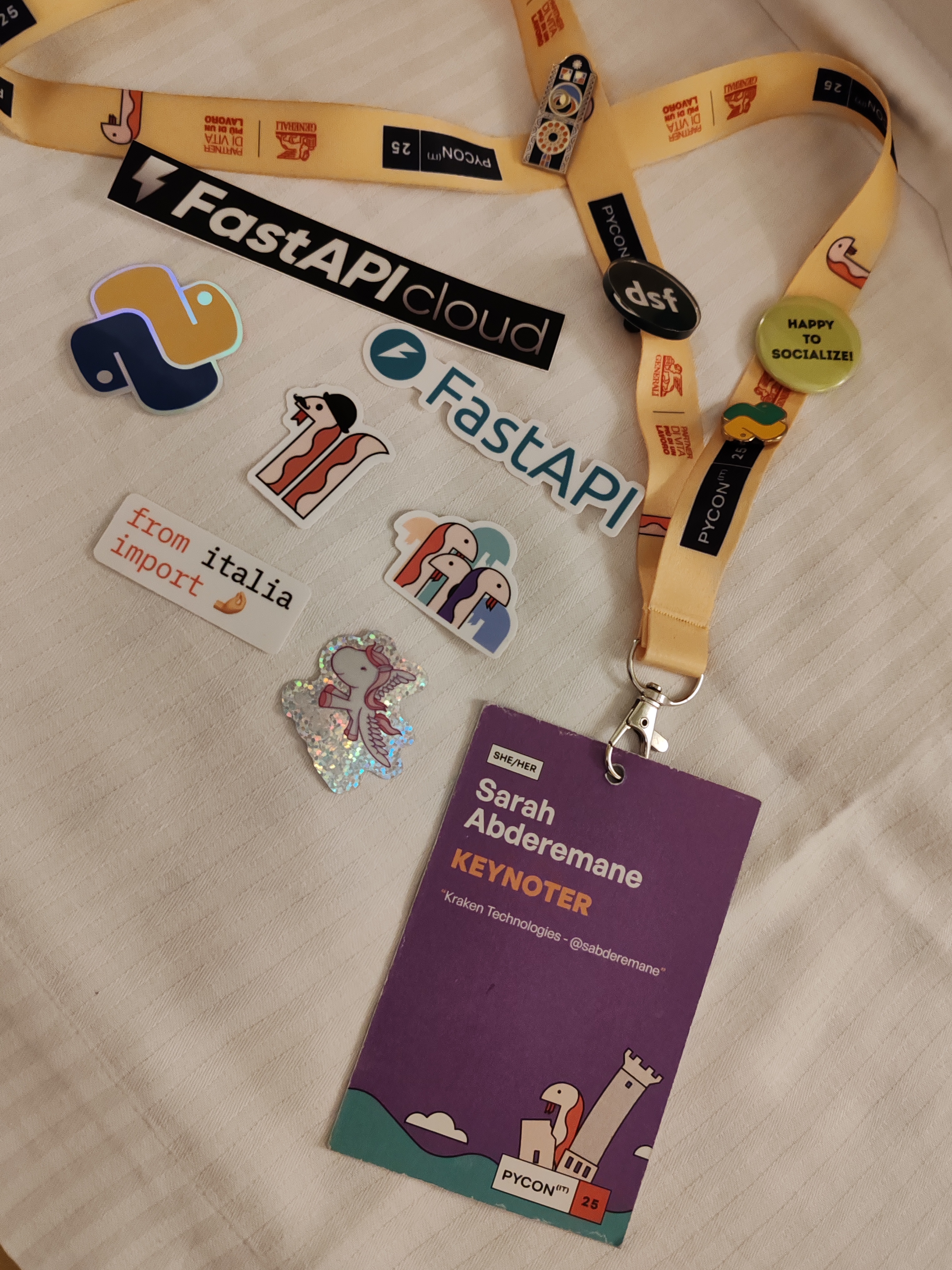My keynoter badge for PyCon IT with some stickers, FastAPI stickers, PyCon IT stickers and Django pony sticker.